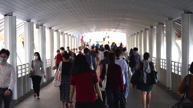 许多人走在桥上的慢动作下班后的公共交通系统在崇nonsi BTS站，泰国曼谷。