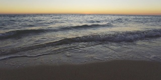 日落之后，海面平静，小波浪冲刷着沙滩