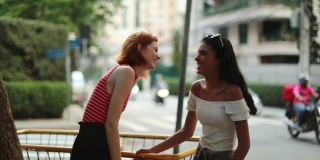 两个朋友在街上互相交谈。多种族女友一起在人行道上聊天