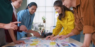 亚洲用户体验开发人员和ui设计师手头脑风暴关于移动应用界面线框图在桌子上和拍手为成功的设计在现代办公室。创意数字发展机构。移出