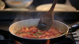 用平底锅煎西红柿和辣椒，准备饭菜，用搅拌勺搅拌食物视频素材模板下载