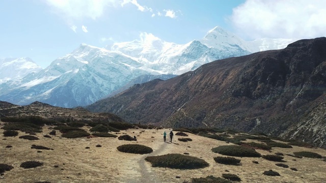 一对夫妇在尼泊尔喜马拉雅山Annapurna马戏团徒步旅行的Manang山谷，在Annapurna链和Gangapurna的景色。干燥和荒凉的景观。白雪覆盖着高耸的山峰。