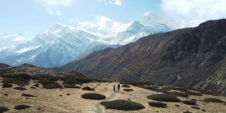 一对夫妇在尼泊尔喜马拉雅山Annapurna马戏团徒步旅行的Manang山谷，在Annapurna链和Gangapurna的景色。干燥和荒凉的景观。白雪覆盖着高耸的山峰。