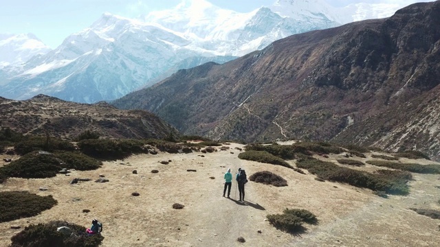 一对夫妇在尼泊尔喜马拉雅山Annapurna马戏团徒步旅行的Manang山谷，在Annapurna链和Gangapurna的景色。干燥和荒凉的景观。白雪覆盖着高耸的山峰。