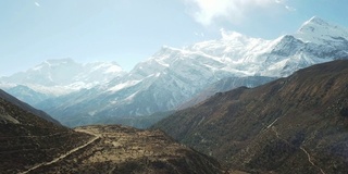 尼泊尔喜马拉雅山马南谷的全景照片。山谷里有一条小河。高山。贫瘠的山坡，中间有一些灌木丛。安纳普尔纳峰电路长途跋涉