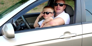 一个严肃的男人和他穿着白色t恤的儿子坐在车里