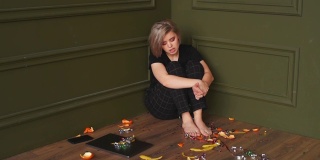 那个不高兴的女孩正坐在角落的地板上唱歌。拍摄一段视频。