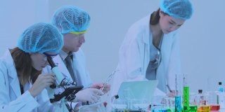 The group scientists research and uses a microscope in a laboratory.