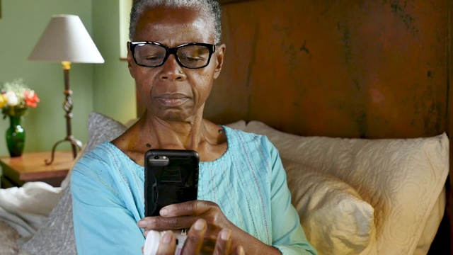 一名黑人妇女用她的手机扫描一个药瓶，并重新填写她的处方
