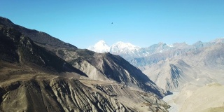 尼泊尔喜马拉雅山马南谷的全景照片。山谷里有一条小河。高山。贫瘠的山坡，中间有一些灌木丛。安纳普尔纳峰电路长途跋涉