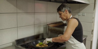 一名妇女在商业厨房的煎锅里准备撒上面包屑的鸡肉