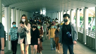 在泰国曼谷的崇诺寺BTS车站，下班高峰期，许多人戴着面具走在大桥上的慢镜头。视频素材模板下载