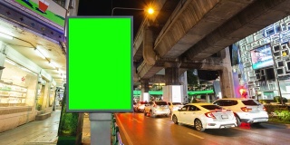 时间流逝，交通长曝光在道路与广告牌绿色屏幕用于广告的街道标志在城市。