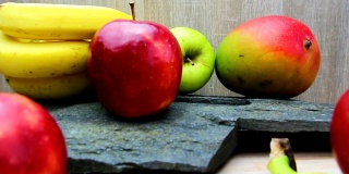 厨房桌上有新鲜水果，石头质感。苹果，芒果和香蕉水果