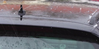 站在外面的一辆车的车顶上，冰雹和雨水在浅浅的下落和跳跃