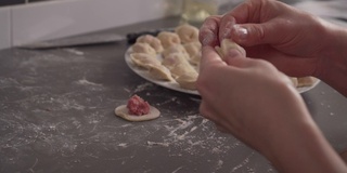 女孩在一张灰色的桌子上包饺子