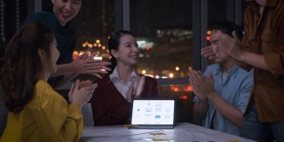 亚洲女性领导者和ux/ui设计师为平板电脑的移动应用界面线框设计在晚上的现代办公室鼓掌。在创意数字开发机构工作到很晚