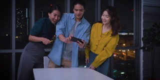 亚洲用户体验开发人员和ui设计师在城市灯光下的现代办公室里研究增强现实(ar)手机应用原型设计。创意数字发展机构