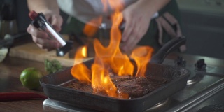 厨师在烤盘上制作火焰风格的牛排。油和酒精用明火燃烧。在烹饪食物。营养在美食厨房。做顿饭。准备吃的食物。美味的菜。