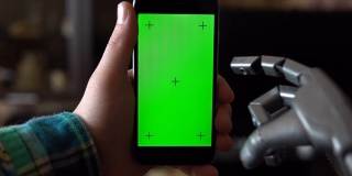 Cyborg uses the phone. Gray mechanical hand swipe up on smartphone with green screen. Chroma key. 4k