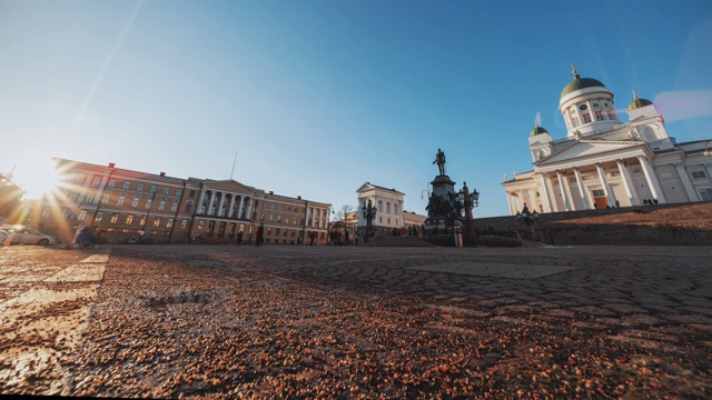 时间流逝:游客聚集在赫尔辛基参议院广场，广场上有亚历山大二世的雕像