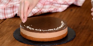 女人在巧克力慕斯蛋糕上点缀坚果。