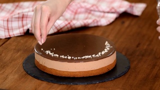 女人在巧克力慕斯蛋糕上点缀坚果。视频素材模板下载