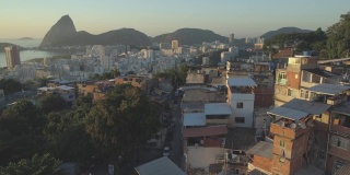 巴西里约热内卢的甜面包山、瓜纳巴拉湾和大洋，冉冉升起的太阳照亮了贫民区的房屋