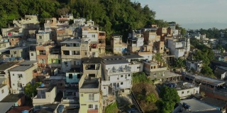 在巴西里约热内卢，日出时，空中追踪经过山顶上阳光明媚的贫民窟房屋