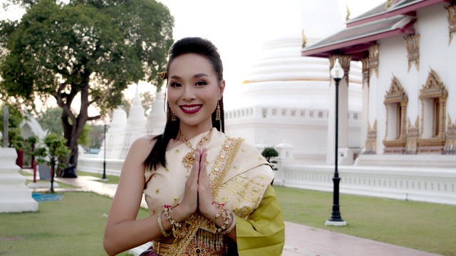 泰国美女身着泰式服饰，在古庙中展现泰国的问候风格。4 k慢动作。
