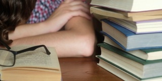一个年轻的学生正在一张木桌上睡觉，书打开着