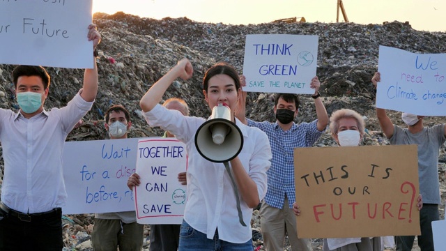 在亚洲的一个巨大的垃圾填埋场上，亚洲领袖女性用扩音器高喊，她们举着环保运动活动家为自然而战的海报。志愿服务、慈善、清洁、生态