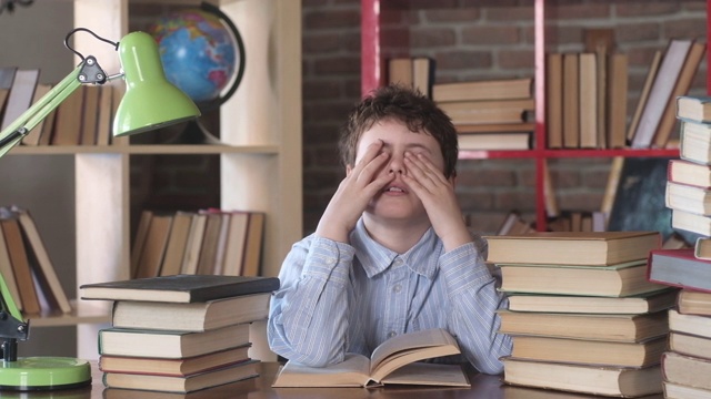 阅读的书籍。一个男生因为疲劳睡在了桌子上。学生揉眼睛。