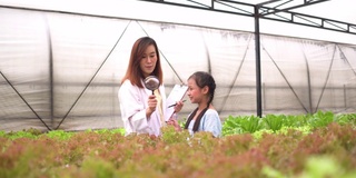 可爱的女孩在科学温室进行实地考察，科学家讲解水培植物的知识