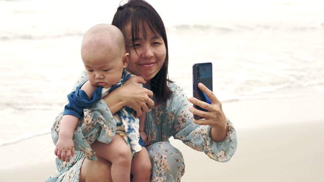 快乐的妈妈和小男孩用智能手机自拍