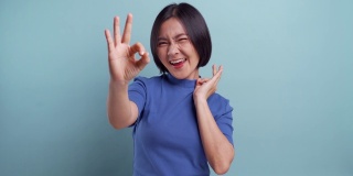 快乐的女人显示OK手势孤立在蓝色背景4K视频