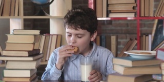 一个男生吃加牛奶的饼干。学生早餐。从学校打破。