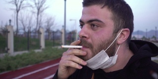 一个戴着面具的年轻人在公园里抽烟
