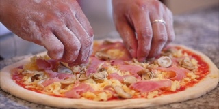真正的意大利辣香肠披萨，烹饪方法，意大利厨师用手指把生面团做成真正的意大利披萨，在披萨上撒上熏香肠片。