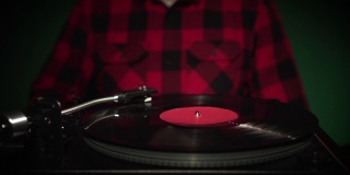 近距离的vintage vinyl audio turntable播放20世纪60年代的LP唱片嬉皮士男子在红色格子衬衫跳舞