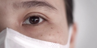 特写亚洲妇女的眼睛与卫生口罩或医疗口罩看着相机