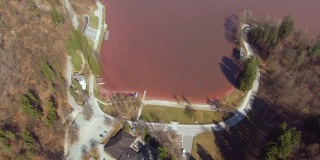 无人机:在空旷的道路上飞行，环绕着一个充满红色水的湖。