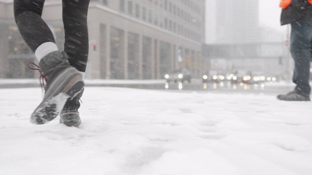 低角度拍摄的女人在城市的雪中行走