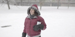 一个迷人的欧亚女人站在下雪的公园里