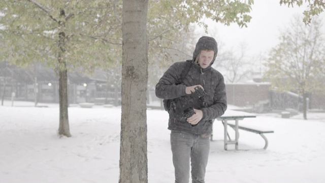 一个年轻人在雪地里调整相机设备的慢动作镜头