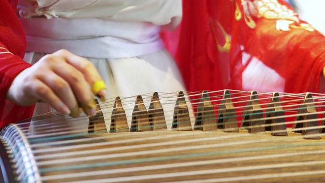 女子弹奏着中国传统乐器，优美动听的古筝