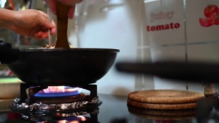 一个亚洲中国女性在家里烹饪中餐炒面在炉灶上烹饪平底锅视频素材模板下载