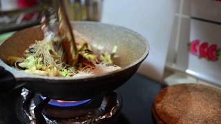 一个亚洲中国女性在家里烹饪中餐炒面在炉灶上烹饪平底锅视频素材模板下载