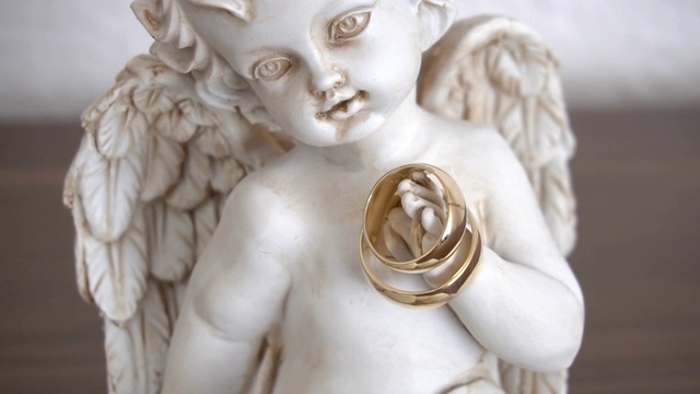 两个结婚戒指在一个天使雕像上