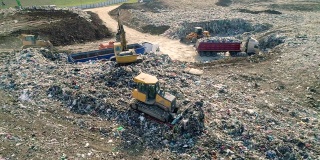 城市垃圾场。推土机沿着垃圾填埋场移动，铲平垃圾。鸟瞰图